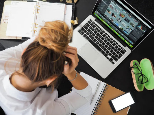 Woman with her head in her hands sitting at a laptop