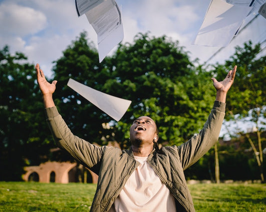 Confident man throwing documents up in the air with an outdoor background
